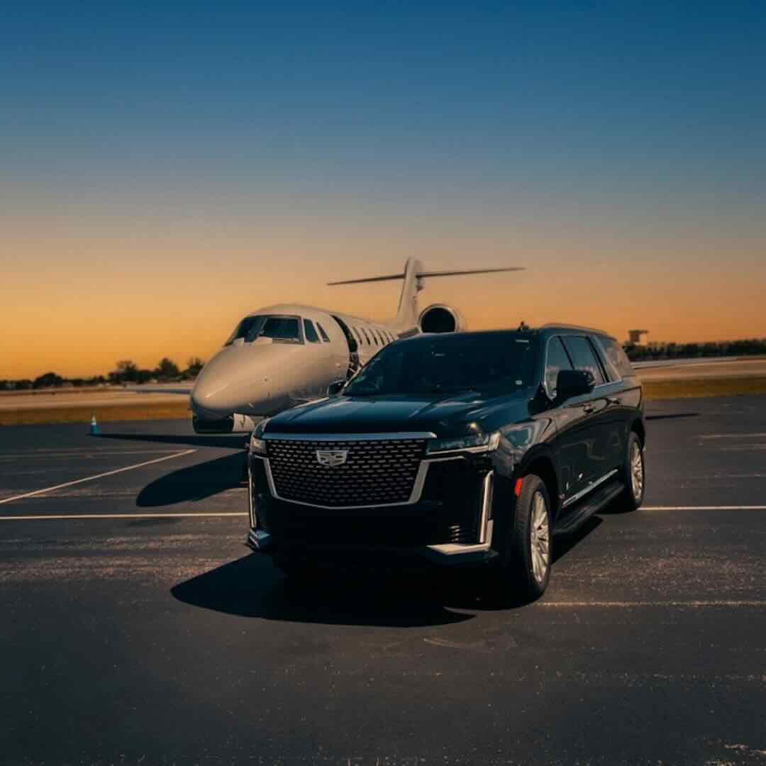 Black Cadillac Escalade SUV parked beside private jet at Orlando executive airport tarmac